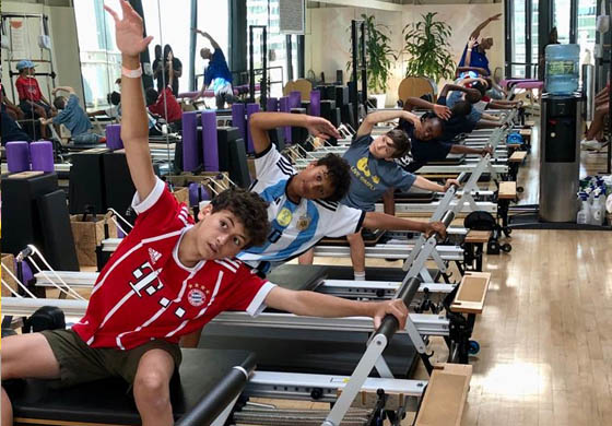 4 boys on Pilates reformers in the Pilates Loft at the Toronto Athletic Club, following instructions by a Pilates instructor